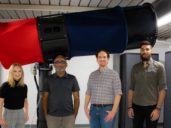 Four people in front of large telescope