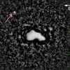 This telescope image shows asteroid Nysa as three-dimensional, bright body, with an arrow pointing at another object, Nysa's tiny moon, located a small distance away. 